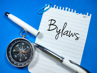 Business concept.Text Bylaws writing on notepaper with open pen and compass on blue background.