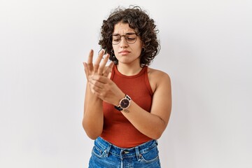 Young hispanic woman wearing glasses standing over isolated background suffering pain on hands and...