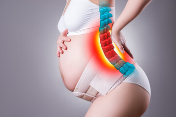 Labor pains, lumbar spine hernia, spinal disc herniation, pregnant woman with back pain on gray...
