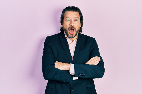 Middle age caucasian man wearing business clothes with arms crossed gesture afraid and shocked with surprise and amazed expression, fear and excited face.