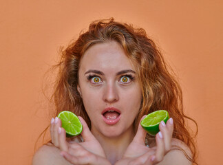 Ginger woman playing with lime on orange background
