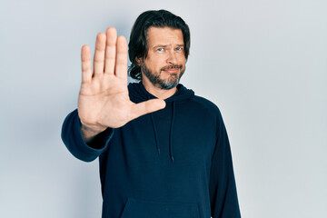Middle age caucasian man wearing casual sweatshirt doing stop sing with palm of the hand. warning...