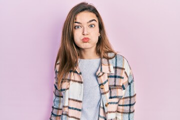 Young caucasian girl wearing casual clothes puffing cheeks with funny face. mouth inflated with air, crazy expression.