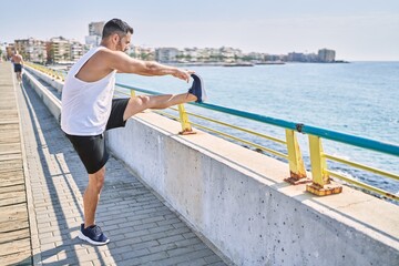 Hispanic man stretching legs after working out outdoors on a sunny day