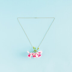 Creative idea of necklace and pink blooming flowers as pendant. Minimal .jewelry flat lay concept.