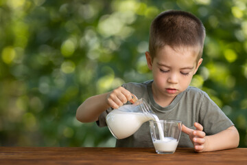 little independent boy pouring milk into glass