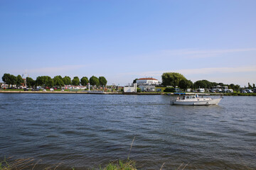 Fototapeta premium Roermond (Marina Resort Oolderhuuske), July 9. 2021: View over river Maas on island with campsite against blue summer sky
