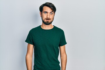 Young hispanic man wearing casual white tshirt puffing cheeks with funny face. mouth inflated with air, crazy expression.