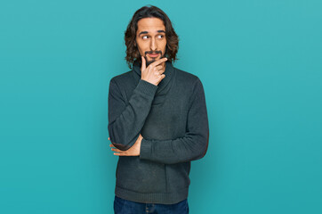 Young hispanic man wearing casual clothes with hand on chin thinking about question, pensive expression. smiling with thoughtful face. doubt concept.