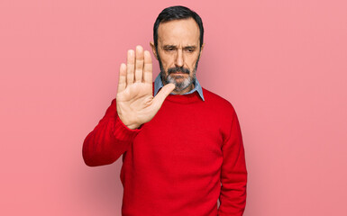 Middle age hispanic man wearing casual clothes doing stop sing with palm of the hand. warning...