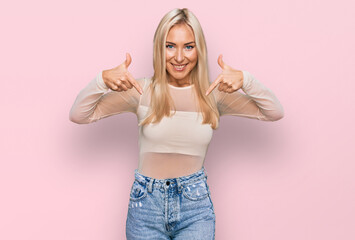 Young blonde woman wearing casual clothes looking confident with smile on face, pointing oneself...
