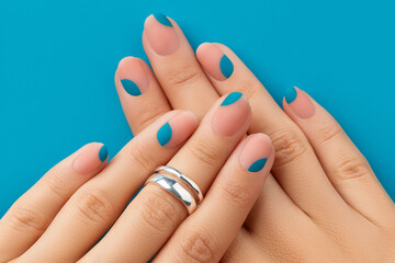 Close up womans hands with summer manicure on blue background. Manicure design trends