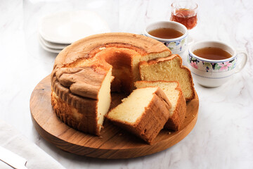 Slice of Fluffly Vanilla Chiffon Cake or Sponge Cake on Wooden Plate, Served with Tea and Honey. Bright Food Photography Concept for Bakery. Selected Focus