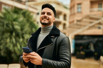 Young arab man smiling happy using smartphone at the city.