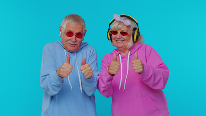 Mature stylish grandparents pensioners listening music via headphones and dancing disco fooling...