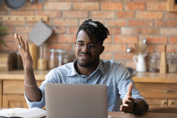 Annoyed millennial African guy upset about problems with computer, online app, virtual services...