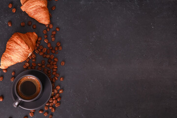 Fresh baked croissants, mug of expresso on dark concrete table. Cup of hot coffee, beans, buns,...