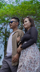 young couple holding hands and walking together in the park
