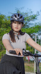 young asian woman enjoying cycling when stopped in summer morning