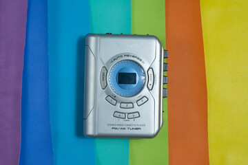 picture of silver colored portable cassette player, in rainbow color background.