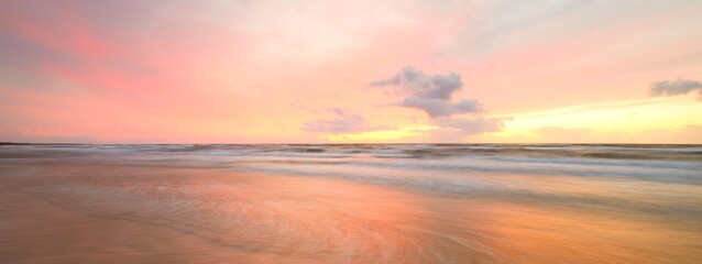 Baltic sea at sunset. Dramatic sky, blue and pink glowing clouds, soft golden sunlight. Waves,...