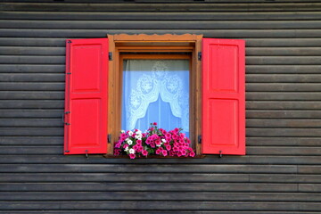 Fototapeta na wymiar finestra di legno rossa e fiori, wooden window and flowers