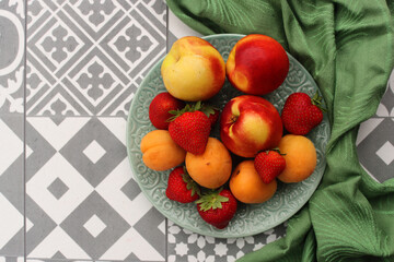 Vibrant colors of fresh organic fruits and berries. Apricots, peaches, blueberry and strawberry on a table, fabric background. Eating fresh concept. 