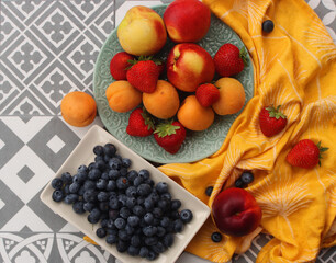Fresh fruits and berries on a table. Juicy summer fruits still life. top view photo of nectarines, apricots, strawberry. Healthy eating concept. 