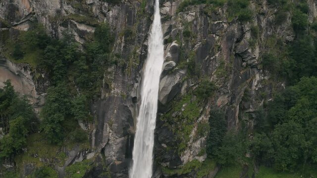 Aerial view of an incredible steep waterfall surrounded by the lush vegetation of the forest near Cevio, Ticino, Switzerland.