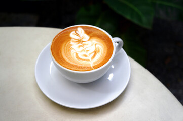 Close up of Hot cappuccino white coffee cup with heart shape latte art on table at caff food and drink concept.                                