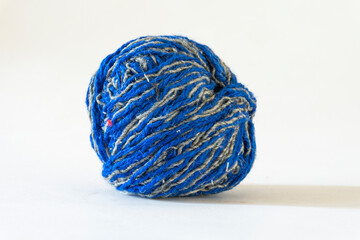 Side view close-up of an isolated blue and grey wool thread ball on white background
