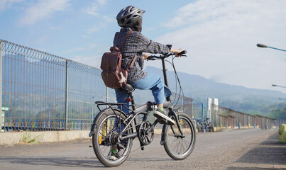 Fototapeta na wymiar Young Asian woman break ride bicycle before go to work