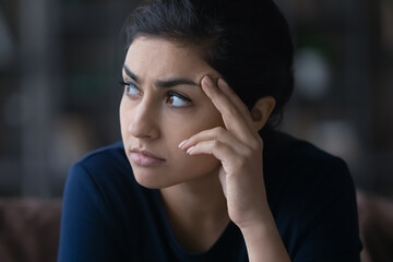 Pensive unhappy young Indian woman look in distance thinking pondering of life problems. Thoughtful millennial mixed race female feel worried anxious about relations. Dilemma, solution concept.