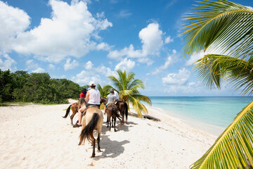 Rearview of a group of People on horseback at a tropical beach on the island of Cozumel in Mexico