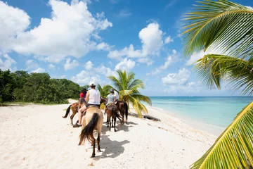 Foto auf Acrylglas Rearview of a group of People on horseback at a tropical beach on the island of Cozumel in Mexico © Marco B.