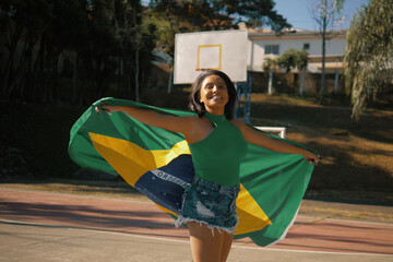 Black girl with Brazilian flag on a soccer field.