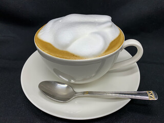 a cup of cappuccino coffee in close-up on a black background