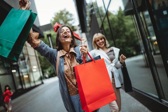 Beautiful happy women with shopping bags walking and having fun