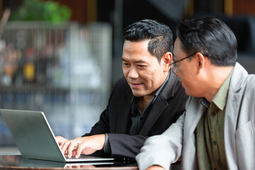 Happy smiling businessmen talking, sharing ideas, discussing planing with computer laptop in modern office. business, people, office concept