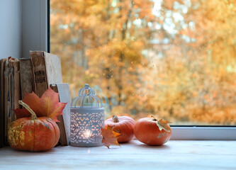 lantern, orange pumpkins and books on windowsill. autumn seasonal composition. symbol of fall time. Mabon, thanksgiving and halloween holiday concept. home comfort.