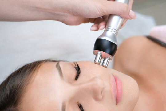 Young woman getting RF face lifting procedure in beauty salon.