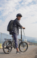 asian young man with backpack having rest after ride bicycle