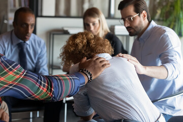 Supportive multiracial employees comfort caress unhappy upset female colleague coworker at team...