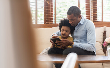 Happy Black African American Brazilian father and little boy using digital tablet