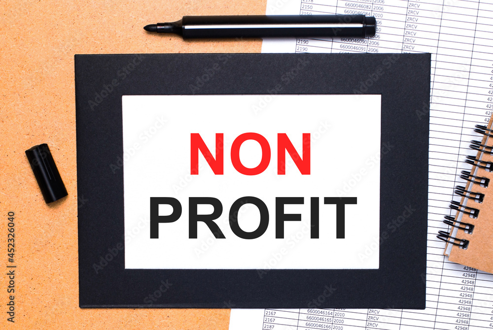 Poster on a wooden table, there is a black open marker, a brown notepad and a sheet of paper in a black fra