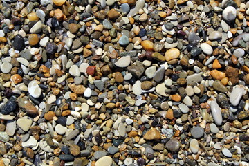 Texture of small raw stones that lie on the seashore.