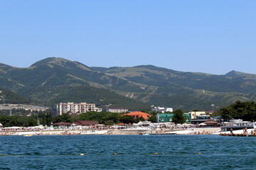 Fototapeta na wymiar Seascape. View from the sea. Summer beach with many people vacationing by the sea on a hot day.