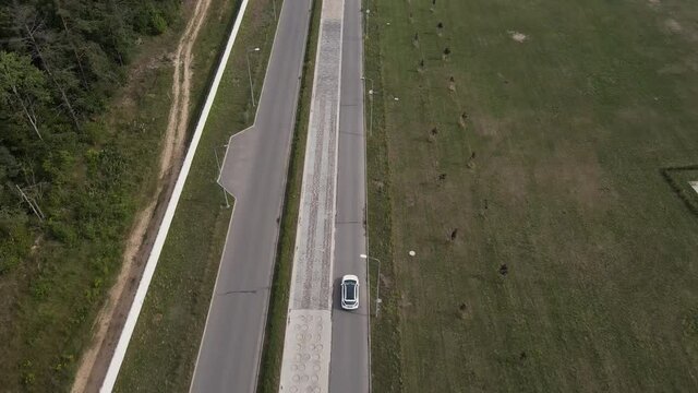 Aerial view of an new electric car doing a lap on the test track. Wide shot of electric car test-drive. Green energy concept.