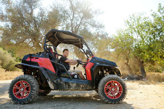 Mature handsome man driving buggy car on sandy hills of Cyprus or Greek in summer. Off road extreme trip