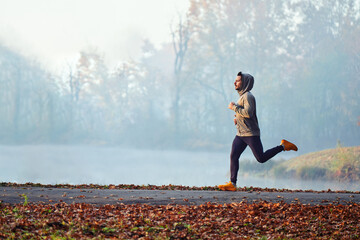 Adult male running in park at autumn morning